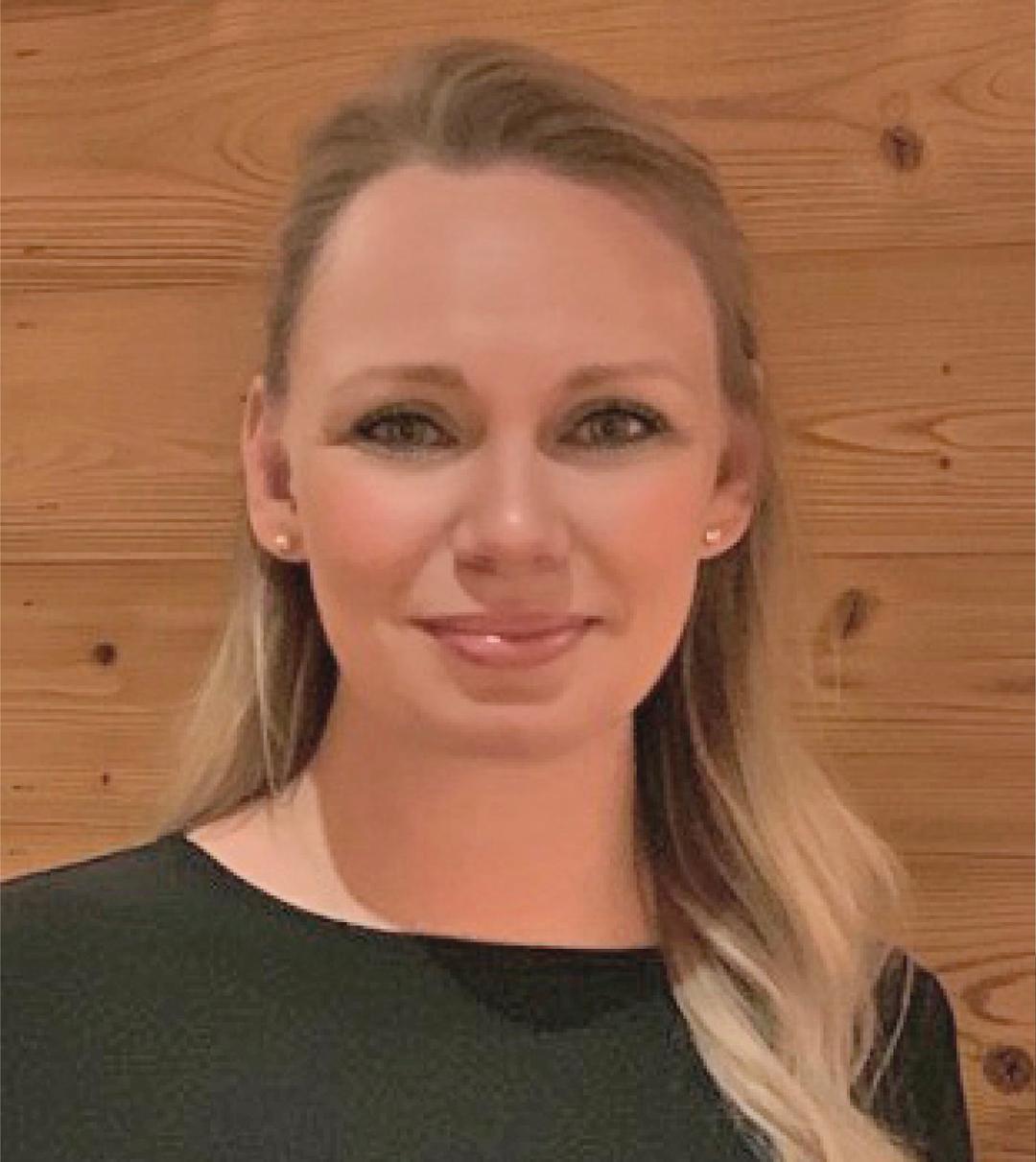 en kvinna ler och tittar in i kameran