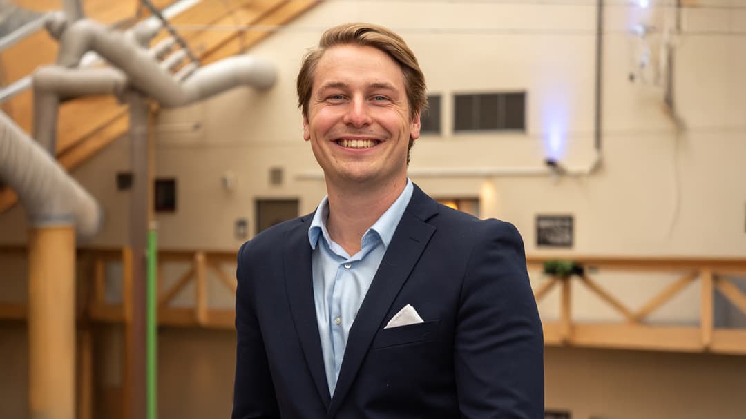 En man i kavaj ler mot kameran