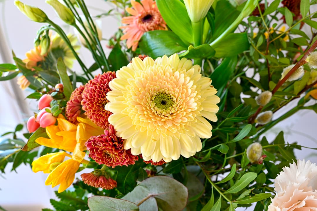 En blombukett med olika blommor i färgerna gul, grön och rosa