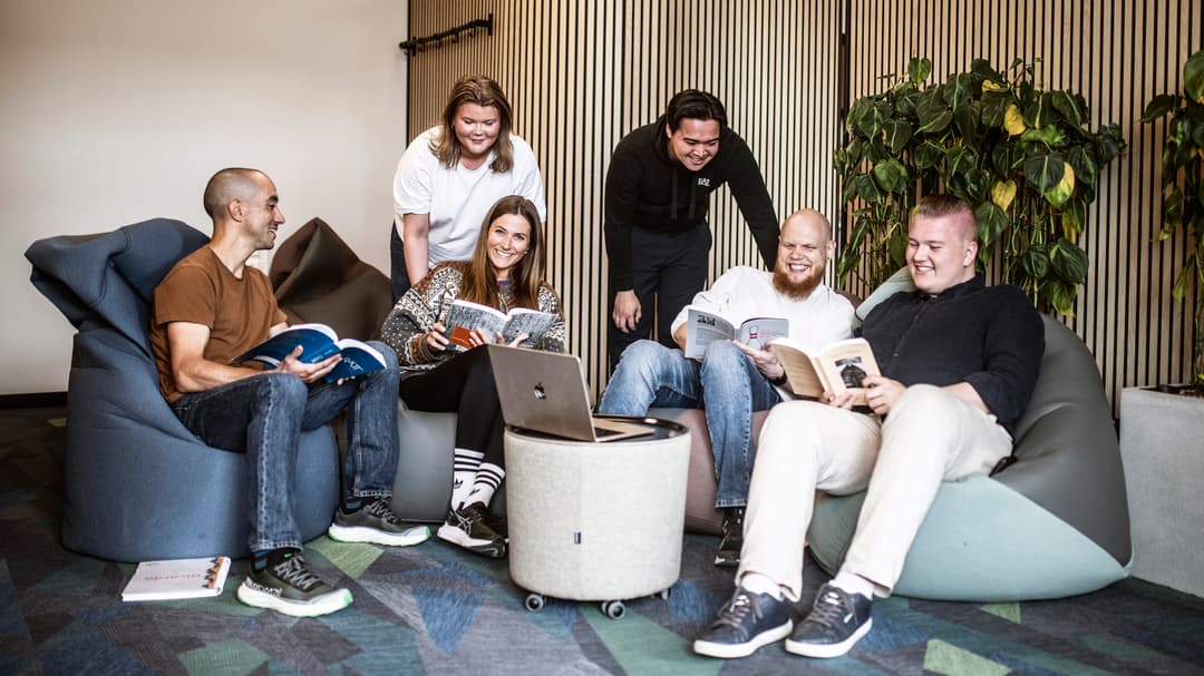 Fyra manliga och två kvinnliga studenter som sitter och pluggar tillsammans med böcker och laptops.