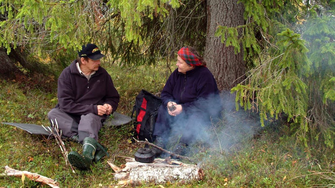 En man och en kvinna samtalar vid en kaffeeld under en gran.