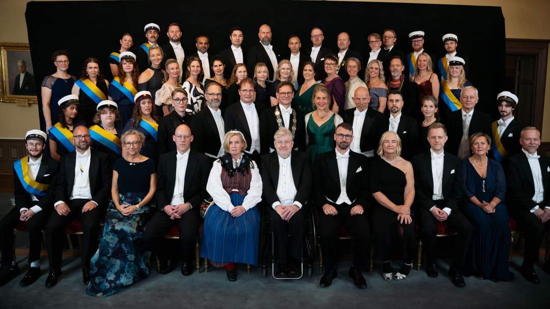 Gruppbild med högtidsklädda personer som sitter och står.