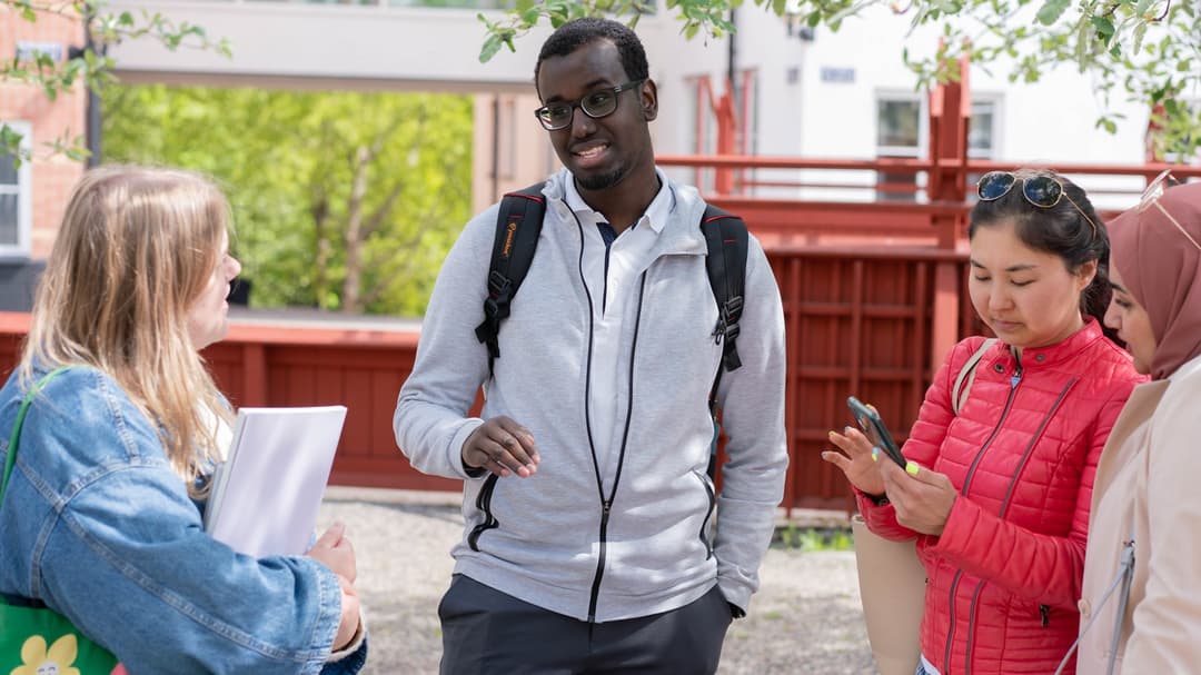 En grupp studenter som står och pratar med varandra utanför campus. 