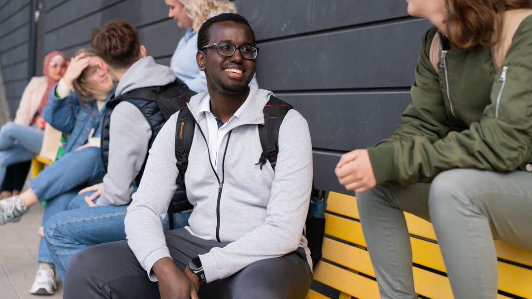 Studenter som sitter på en gul bänk. 