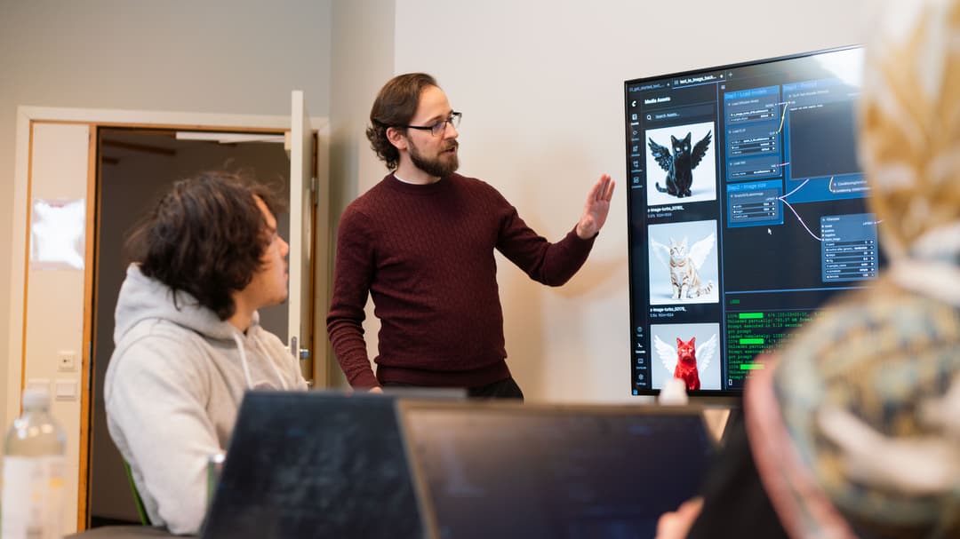 A man stands at a screen and teaches. The screen shows AI code.