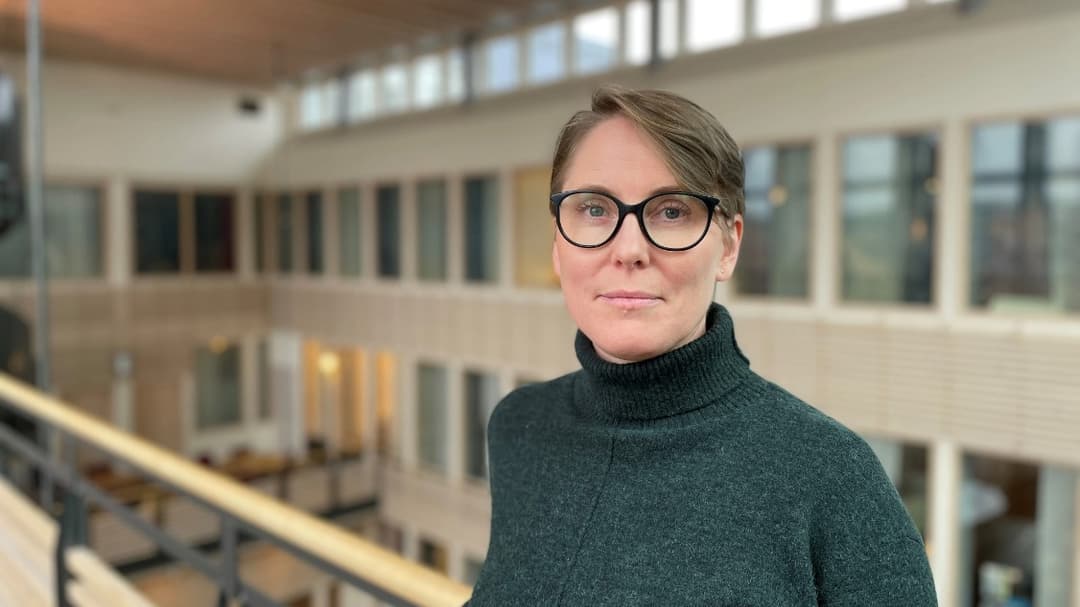 Porträttfoto av en kvinna med brunt hår och svarta glasögon
