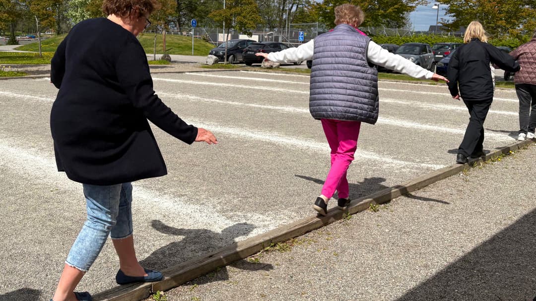 Kvinnor balanserar på en smal bräda vid en grusplan