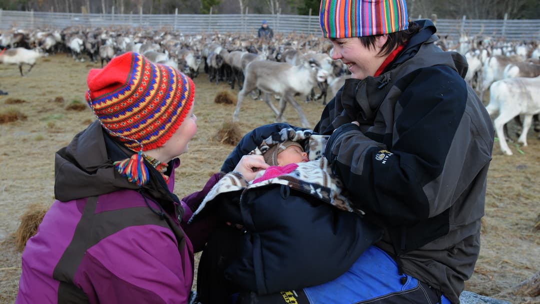 Kvinna med två barn i ett rengärde.