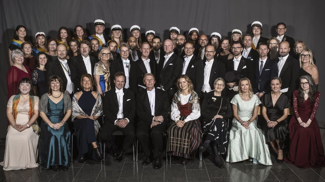 A group photo of just over fifty well-dressed people.