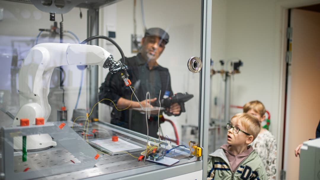 Kids looking at a robot arm in the lab.