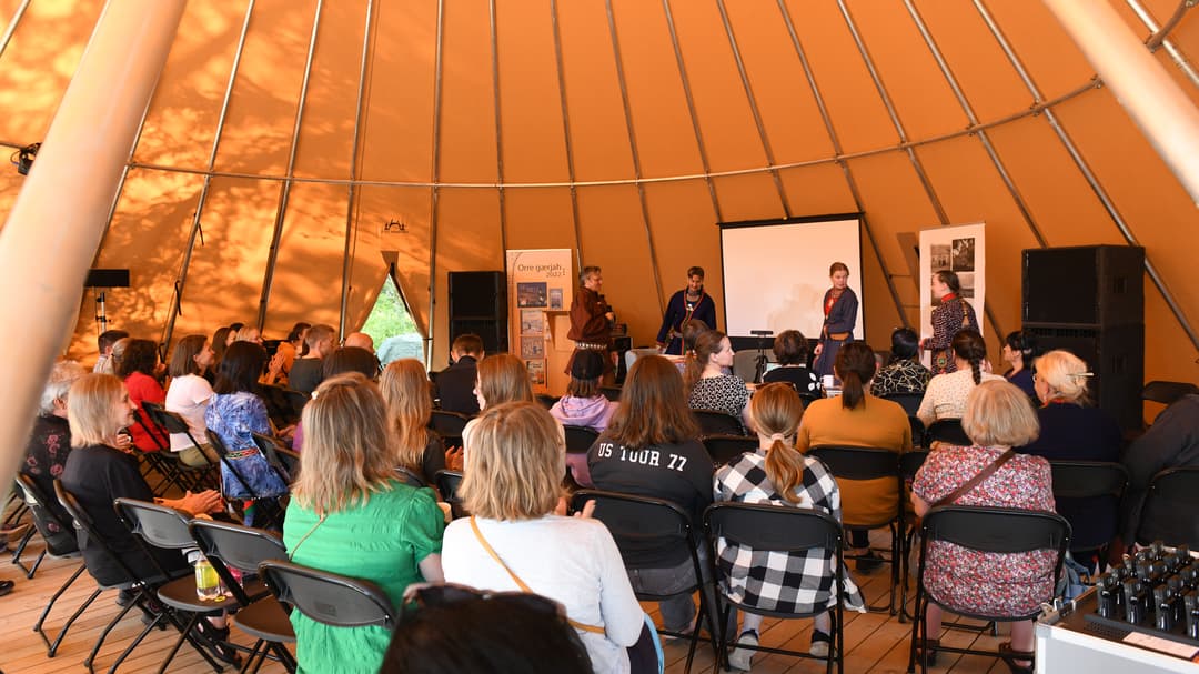 Publik lyssnar på ett panelsamtal i en stor tältkåta.