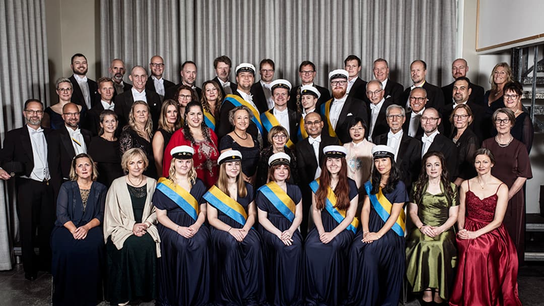 Gruppbild med högtidsklädda personer som sitter och står.