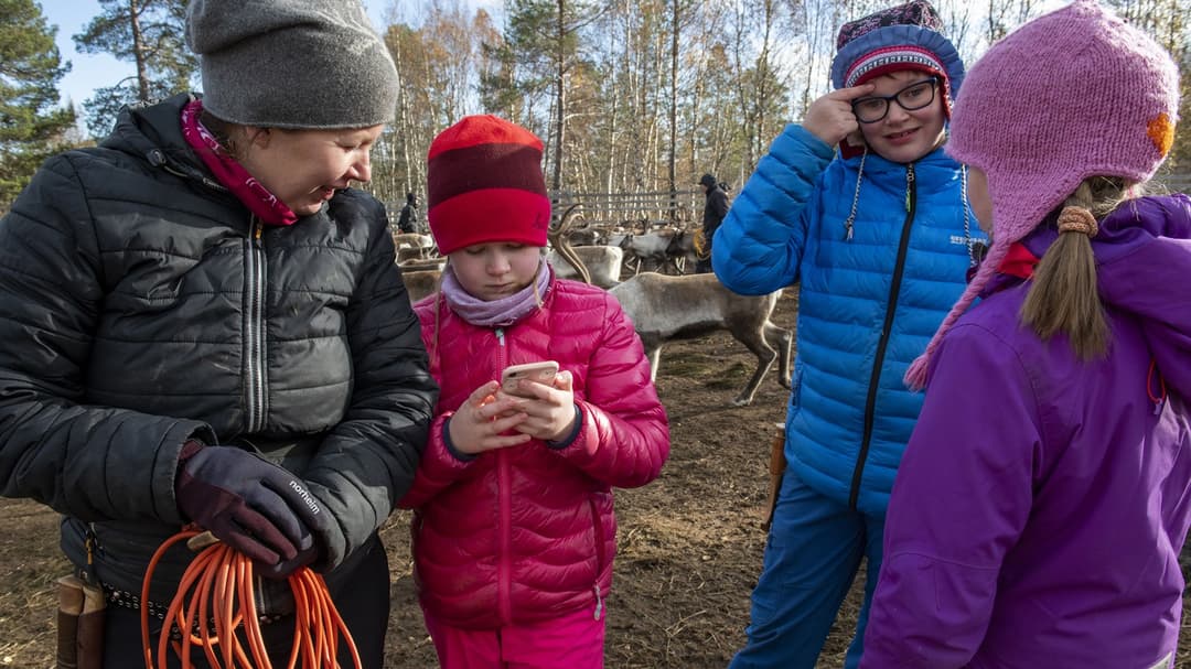 En flicka visar något på sin mobil för en kvinna.