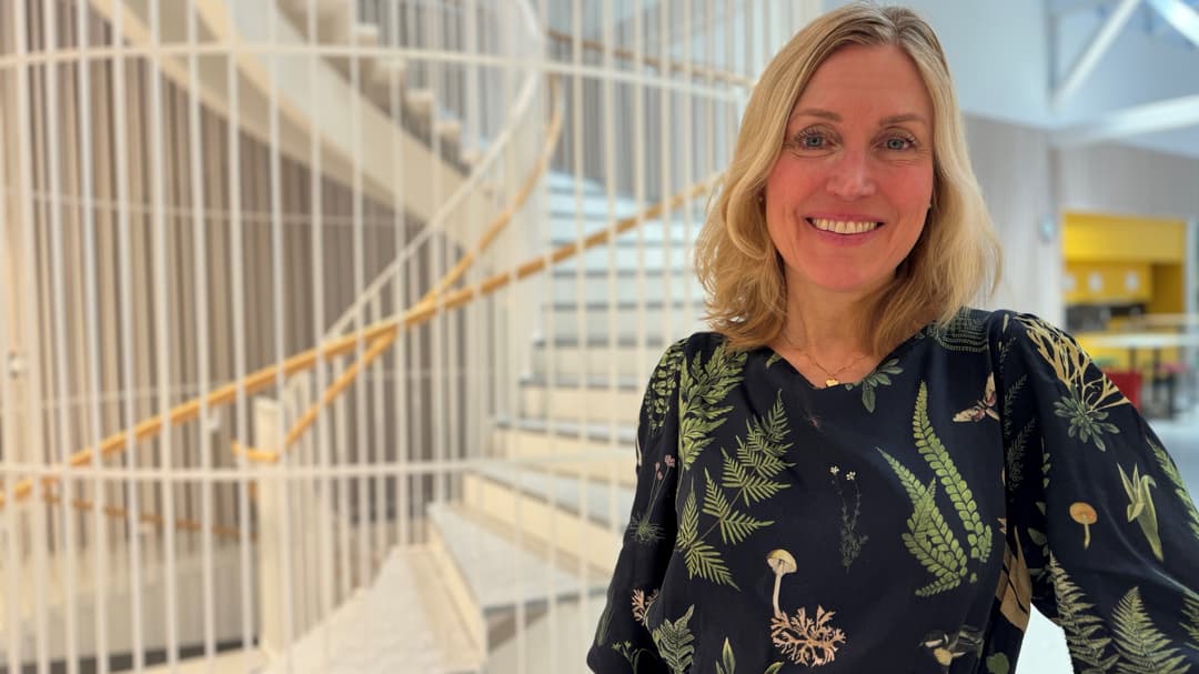 Leende kvinna i en svart klänning med gröna blommor