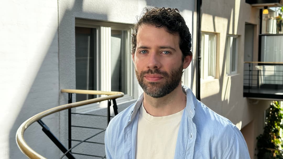A man with dark hair and a white tshirt and a blue shirt