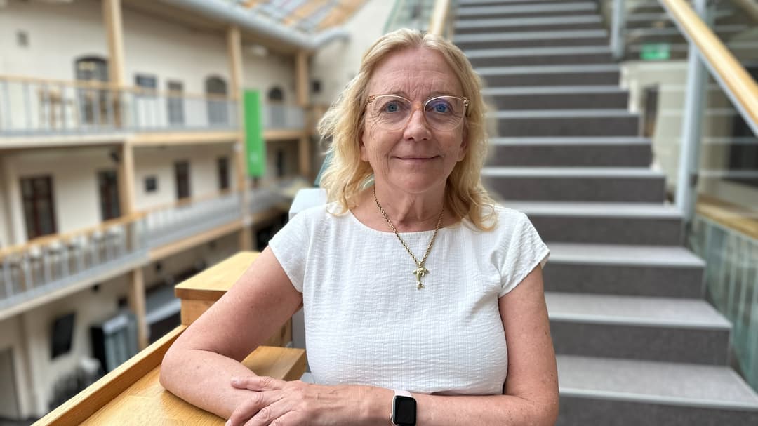 Porträttfoto av en blond kvinna ståendes framför en trappa