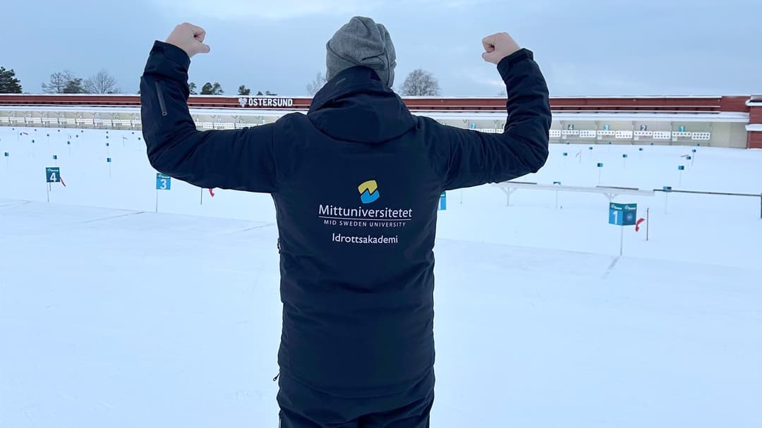 Man visar texten på ryggen av sin jacka med en "jag är stark" pose.