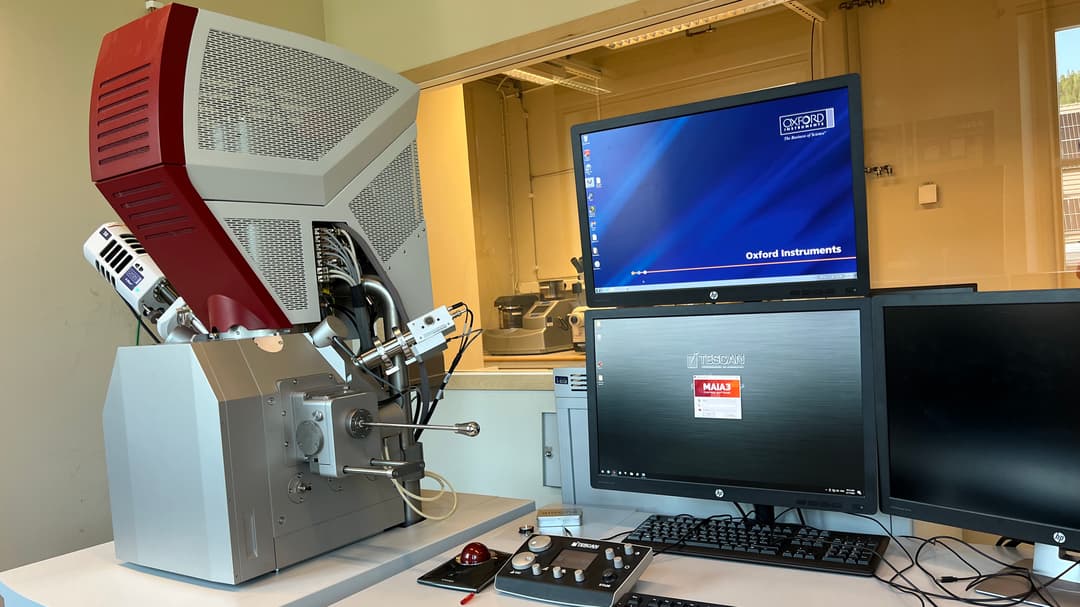 Svepelektronmikroskop med bildskärmar i laboratoriemiljö.
