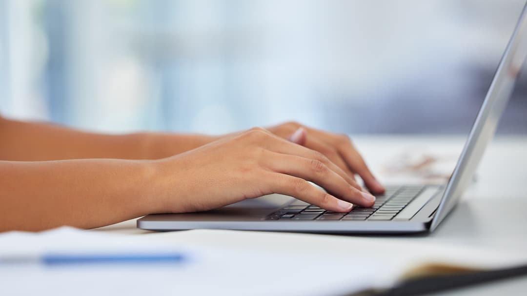 Två händer om skriver på en laptop