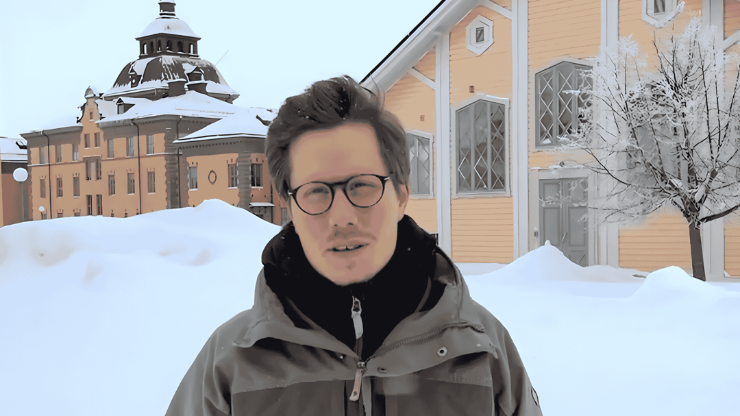 Studenten Simon står ute på gården på Mittuniversitetets campus i Östersund. Det är vinter och mycket snö.