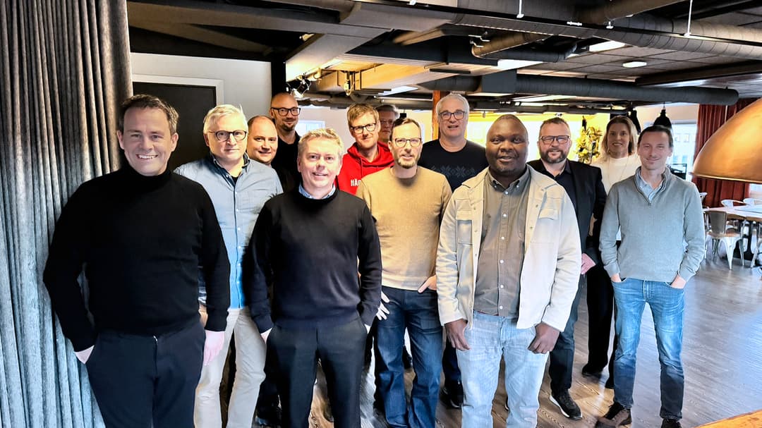 En grupp på 12 personer står mot kameran och ler