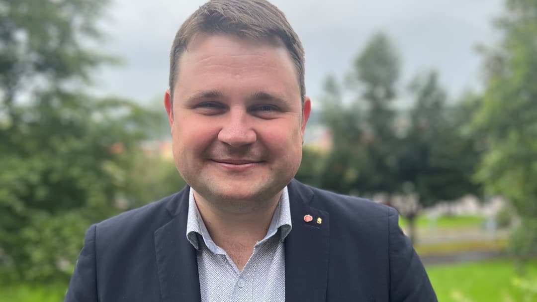 Porträttbild av leende mörkhårig man i mörk kavaj och grå skjorta