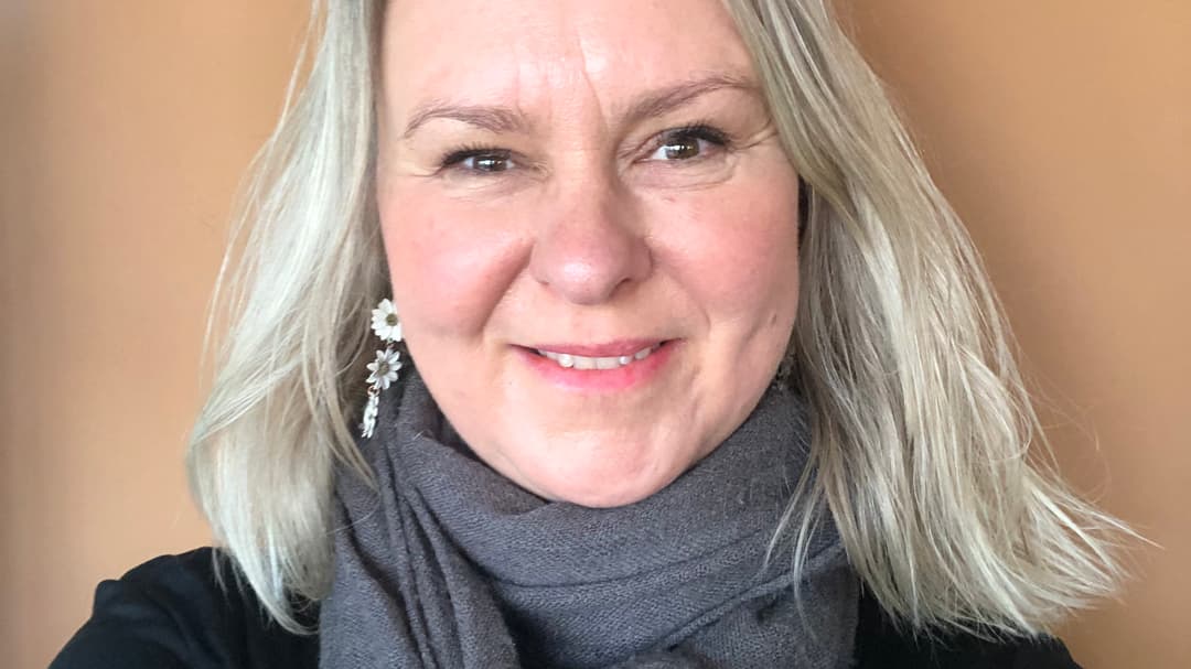 Ett porträttfoto av en blond kvinna mot en ljusbeige bakgrund
