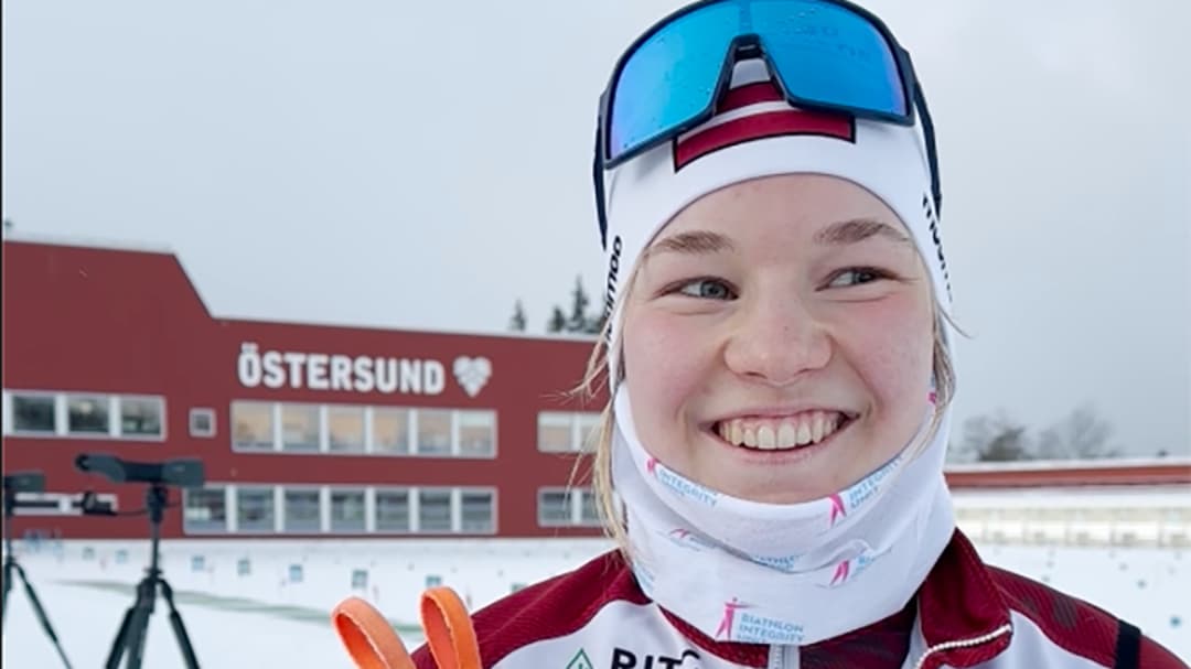 Leende kvinna på skidskyttestadion.