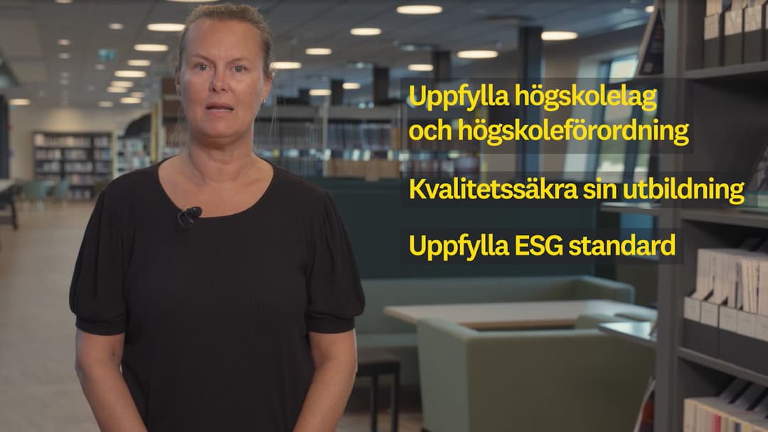 Kvinna med ljust uppsatt hår ståendes i ett kontorslandskap.