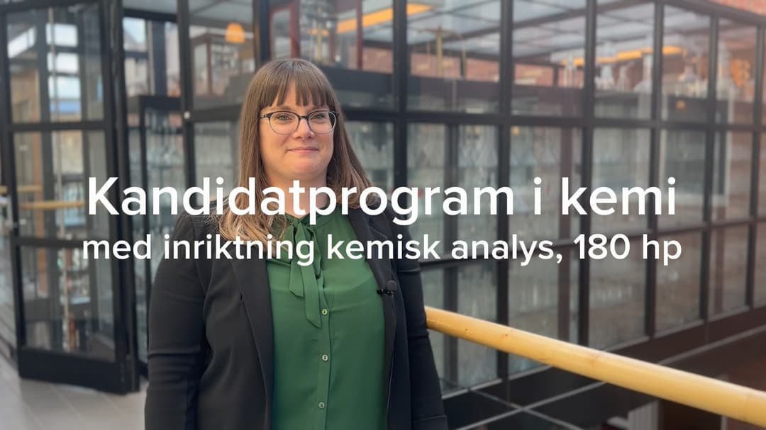 En kvinn ai mörkt hår och mörka kläder står framför en glasvägg