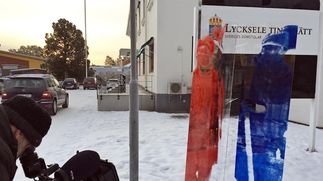 Fotograf tar bild av glas med en röd och en blå same målade på, utanför Lycksele Tingsrätt