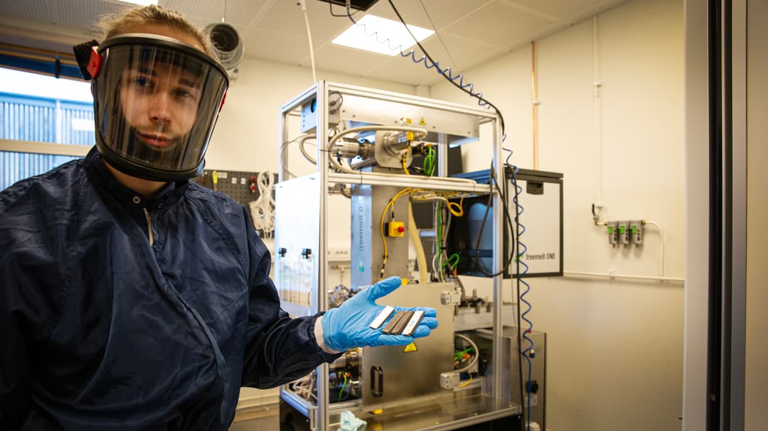 Man står iklädd skyddsdräkt och friskluftsmask och håller i tungstenar.