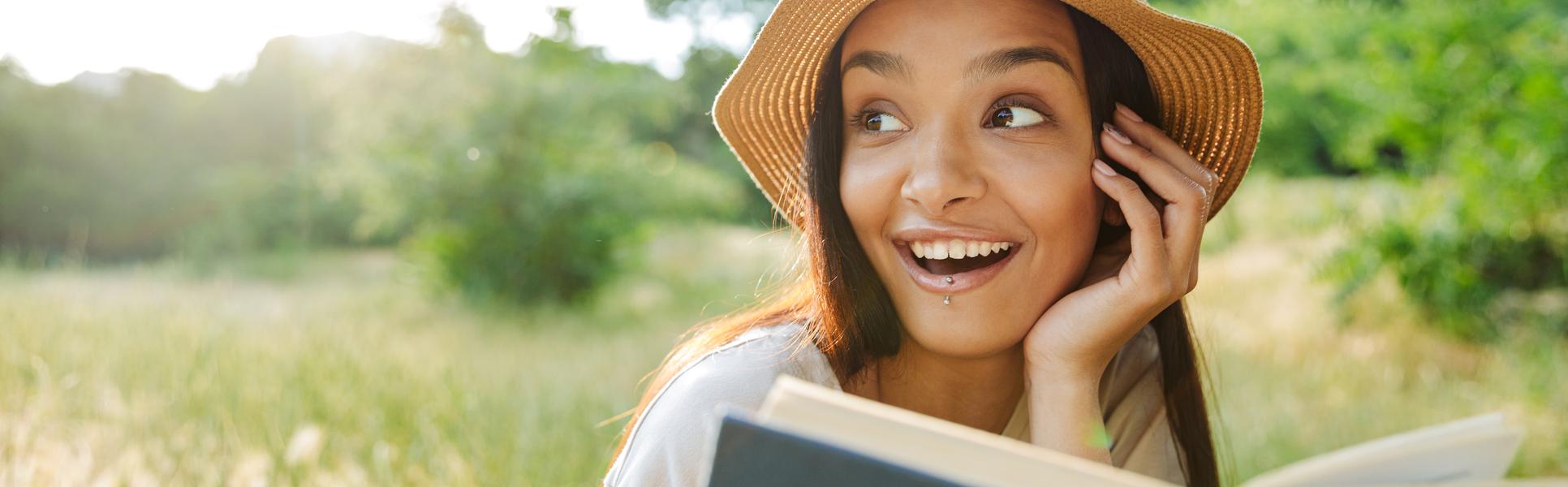 Leende kvinna läser bok i solen