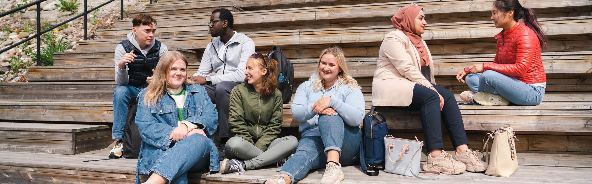 Sju studenter som sitter i en trappa.