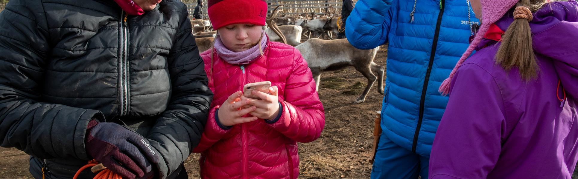 En flicka visar något på sin mobil för en kvinna.