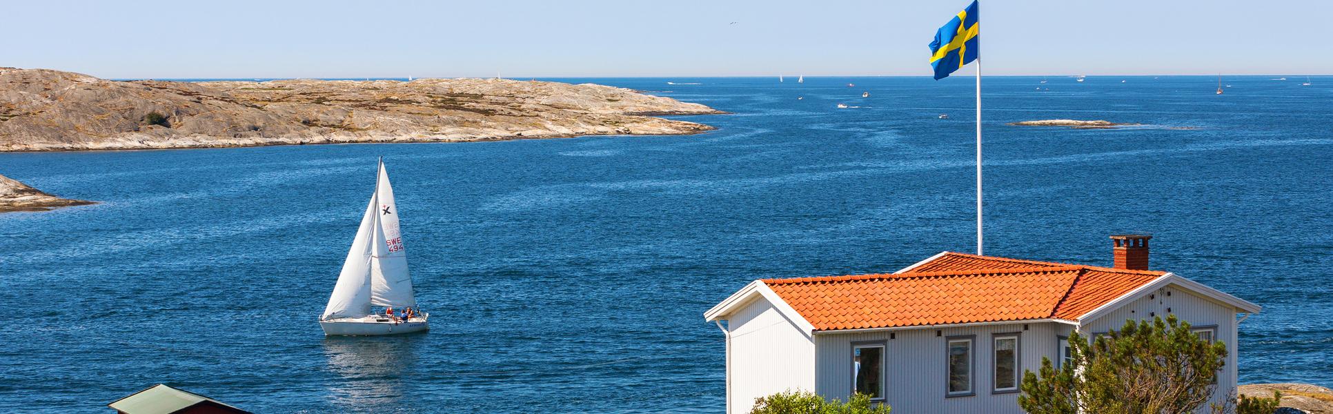 En vy från en skärgård i Sverige med en stuga och svenska flaggan