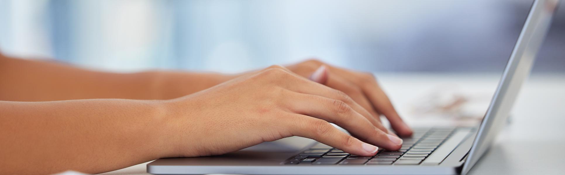 Två händer om skriver på en laptop