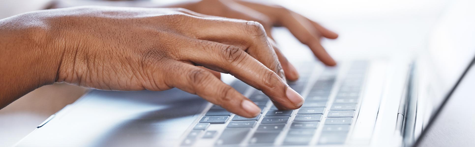 Two hands writing on a laptop