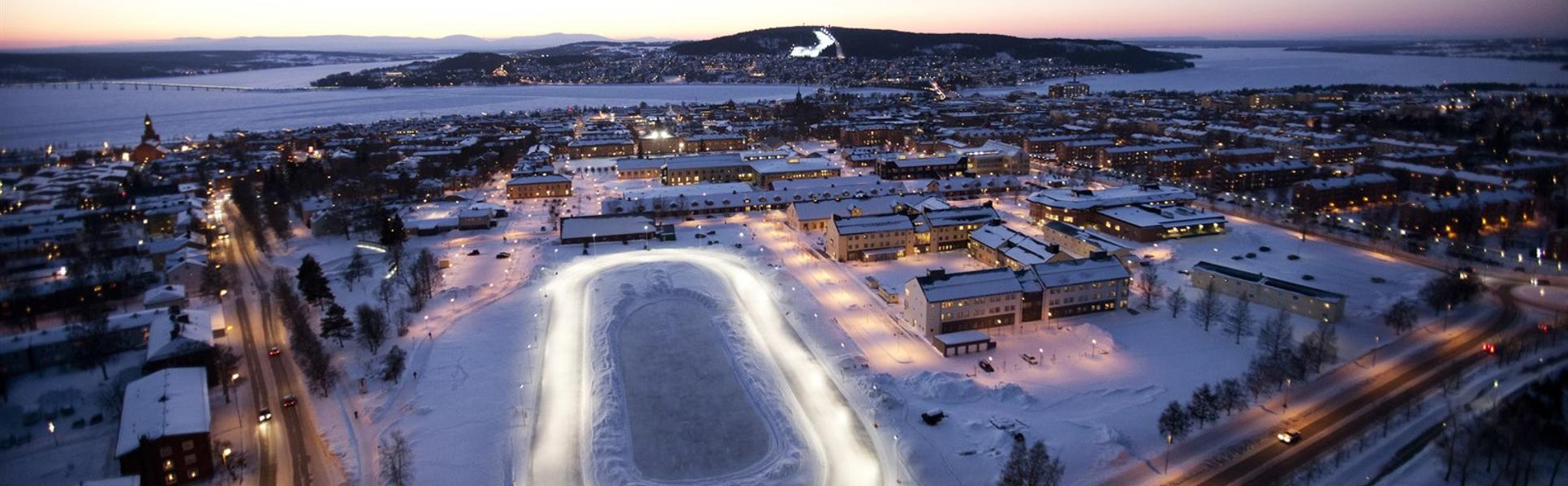 Fågelvy över en stadsbild med en sjö och fjäll i bakgrunden
