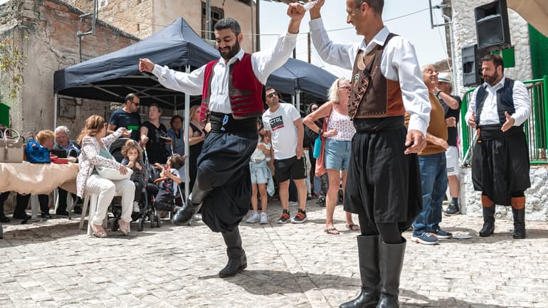 Två cypriotiska män i traditionell cypriotiska dräkter dansar på gatan