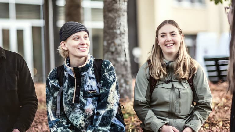 Fyra studenter sitter utomhus på campus i Östersund, de ser glada ut glada och pratar med varandra 