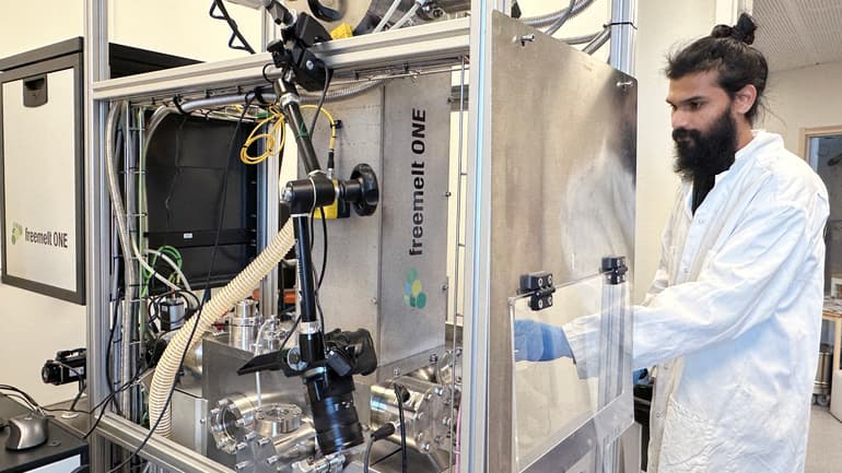 A man in a white lab coat, inside a lab.