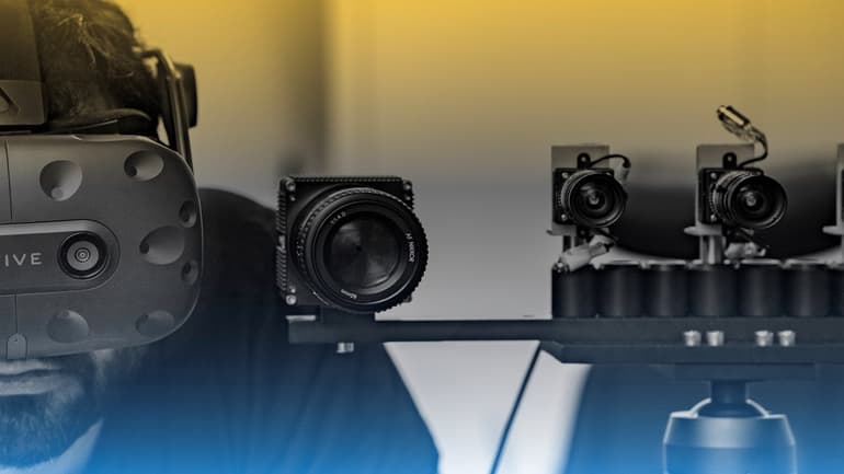 A man with a VR headset on standing next to a set up of smaller cameras.