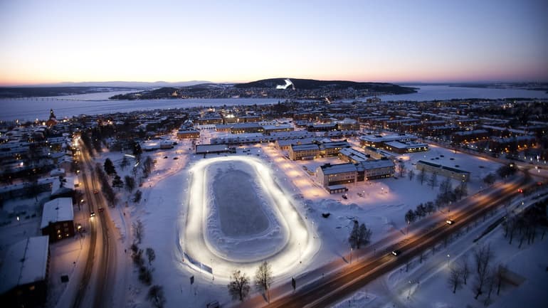 Fågelvy över en stadsbild med en sjö och fjäll i bakgrunden