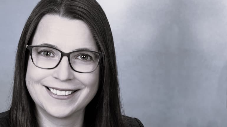 A woman with brown hair and glasses smiles