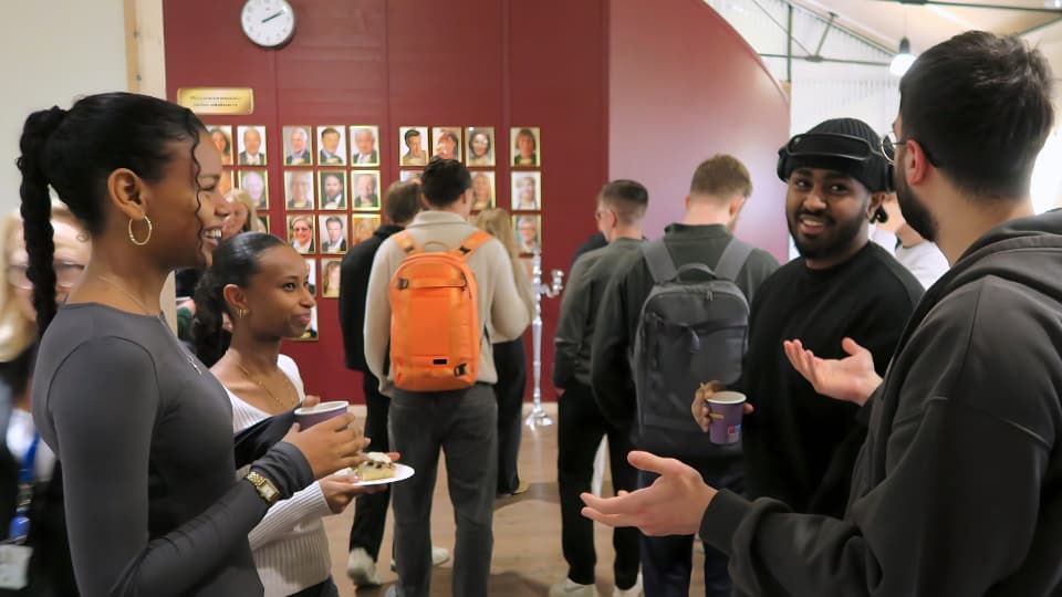 Grupp av studenter som samtalar med varandra under fikapaus