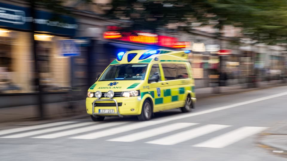 Stor ambulans under utryckning i stadsmiljö.