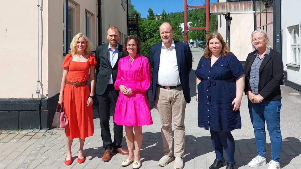 Fyra kvinnor och två män samlade för fotografering