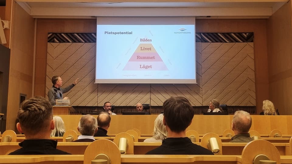 Människor sittandes i en föreläsningssal, lyssnandes till en föreläsare