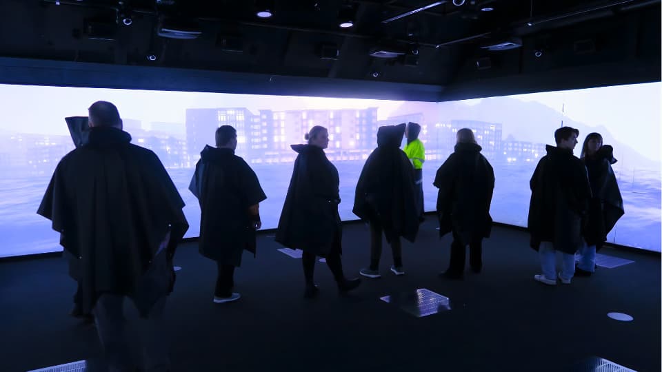 Sju workshopdeltagare står i RCR labbet framför stora bildskärmar